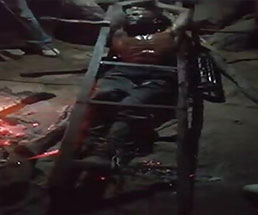 拘束された男性が熱した鉄を押し当てられて拷問を受ける様子